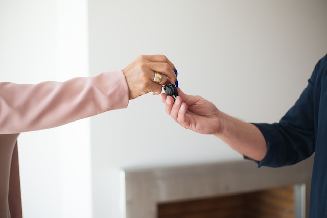 Close up of a person's hand giving keys to another person